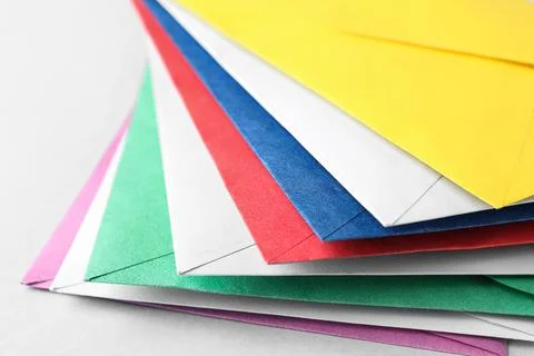 Stack of colorful paper envelopes on light background, closeup Foto stock