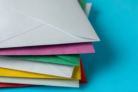 Stack of colorful paper envelopes on light blue background, closeup Foto stock