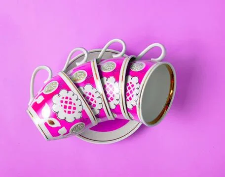 Stack of colorful pink and white coffee mugs on purple background Foto stock