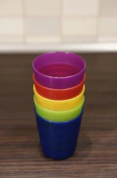 Stack of colorful plastic toy cups on a wooden table Stock Photos