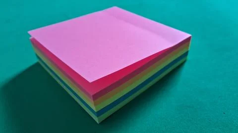 Stack of colorful sticky notes on teal background. Vibrant pastel memo pads for Stock Photos