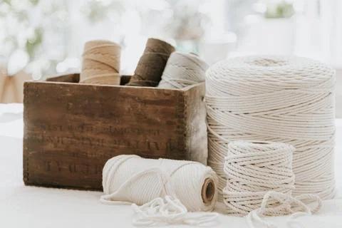Stack of colorful thread spools in a wooden box set against a white background Foto stock