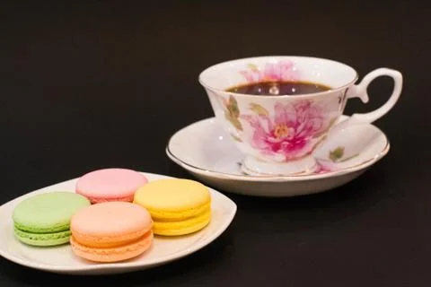 Stack of colourful macaron cookies on plate near coffee cup. Stock Photos