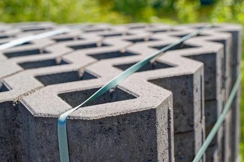 Stack of concrete blocks secured with green straps outdoors on a sunny day .. Stockfoto's