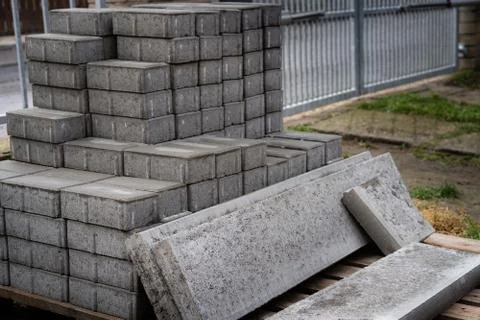 Stack of concrete paving blocks and kerbs on a wooden pallet. Gray concrete s Stock Photos