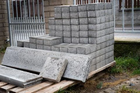 Stack of concrete paving blocks and kerbs on a wooden pallet. Gray concrete s Stock Photos
