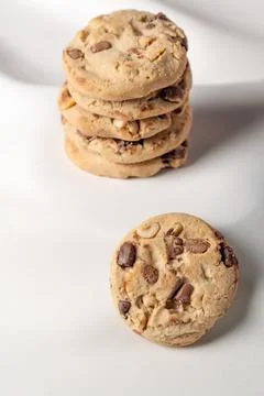 A stack of cookies with nuts and chocolate chips on top on a white background 스톡 사진