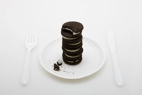 A stack of cookies on a paper plate with a bite missing from the top (studio). 스톡 사진
