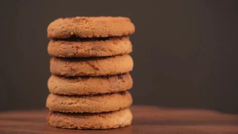 Stack of cookies with pieces of chocolate rotates on brown background. closeup. Video stock 239720050