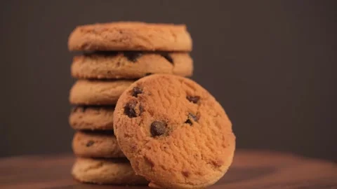 Stack of cookies with pieces of chocolate rotates on brown background. closeup. Stock Footage 247004554