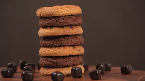 Stack of cookies with scattered pieces of chocolate rotates on brown background. Stock Footage 244321069