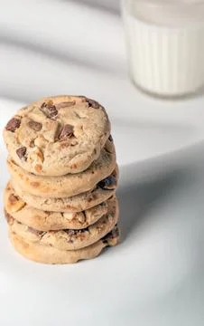 A stack of cookies sits on a table next to a glass of milk 스톡 사진