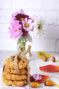 A stack of cookies tied with a rope next to autumn leaves and a vase of flowe Stock Photos