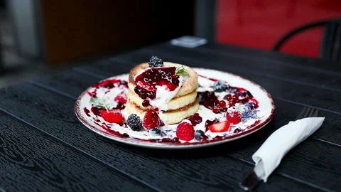 Stack of cottage cheese pancakes syrniki with sour cream and fresh berries on ca Stock Footage 337543147