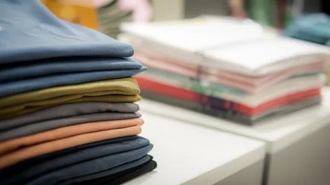 Stack of cotton colorful clothes on table in cloth store. Stock Photos