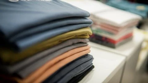 Stack of cotton colorful clothes on table in cloth store. Stock Photos