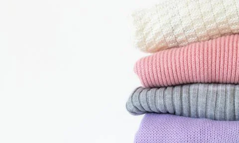 Stack of cozy knitted autumn or winter sweaters isolated on white background Stock Photos
