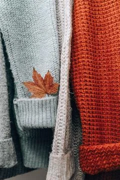 Stack of cozy knitted warm sweater with Autumn fall maple leaf. Sweaters in r Stock Photos