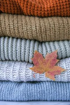 Stack of cozy knitted warm sweater with Autumn fall maple leaf. Sweaters in r Stock Photos