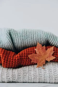 Stack of cozy knitted warm sweater with Autumn fall maple leaf. Sweaters in Foto stock
