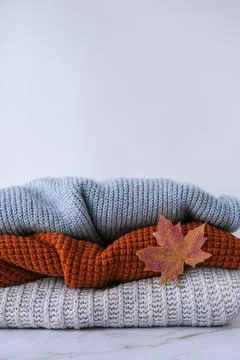 Stack of cozy knitted warm sweater with Autumn fall maple leaf. Sweaters in Foto stock