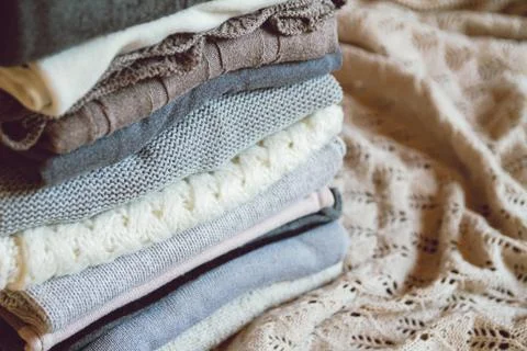 A stack of cozy warm winter clothes lies on the bed Stock Photos