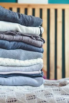 A stack of cozy warm winter clothes lies on the bed Stock Photos