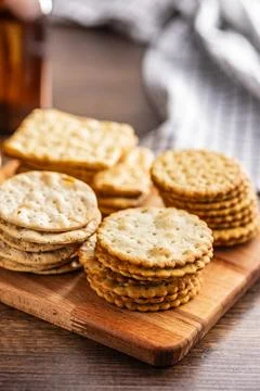A stack of crackers neatly arranged on cutting board on a wooden tabletop. 스톡 사진