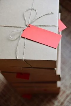 Stack of craft boxes with gifts tied with a cord with tag Stock Photos