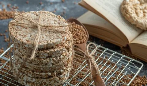 Stack of crispbread, buckwheat and book on marble surface Stock Photos
