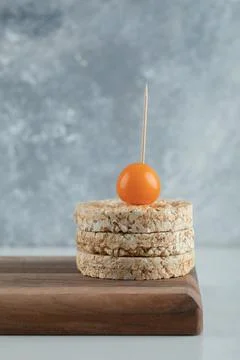 Stack of crispbread with orange cherry tomato on wooden board Stock Photos
