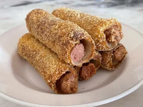 Stack of Crispy Fried Sausage Bread Rolls with Visible Meat Filling Foto stock
