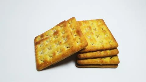 Stack of crispy golden brown cream crackers on white background. Fotos Stock