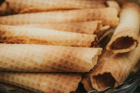 Stack of crispy rolled wafers arranged neatly on a glass plate, showcasing .. Stock Photos