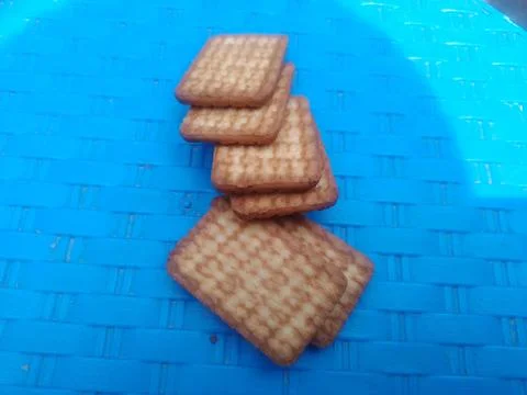 Stack of crispy square crackers on blue. 스톡 사진
