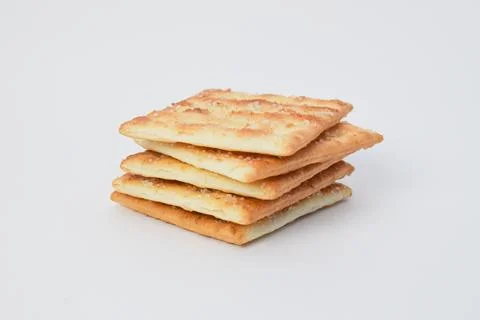 Stack of crispy square crackers isolated on white background, showing golde.. Stock Photos