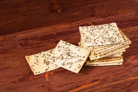 Stack of crispy wheat cakes with sesame seeds, flax and sunflower on a red wo Stock Photos