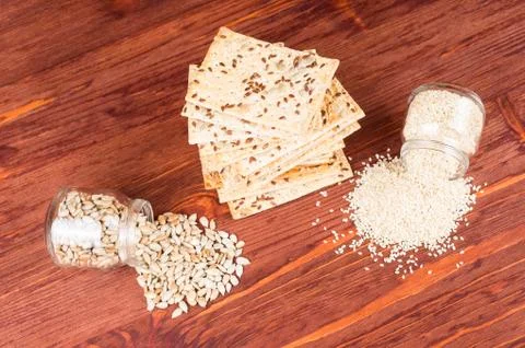 Stack of crispy wheat cakes with sesame seeds, flax and sunflower on a red wo Stock Photos
