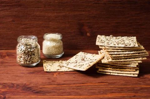 Stack of crispy wheat cakes with sesame seeds, flax and sunflower on a red wo Stock Photos