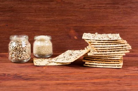 Stack of crispy wheat cakes with sesame seeds, flax and sunflower on a red wo Stock Photos