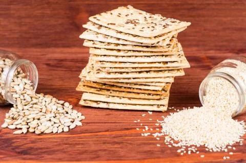 Stack of crispy wheat cakes with sesame seeds, flax and sunflower on a red wo Stock Photos