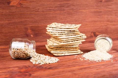 Stack of crispy wheat cakes with sesame seeds, flax and sunflower on a red wo Stock Photos