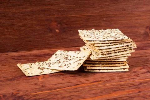 Stack of crispy wheat cakes with sesame seeds, flax and sunflower on a red wo Stock Photos
