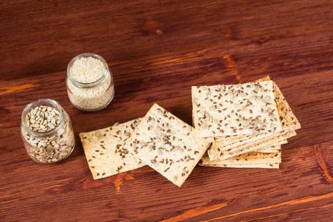 Stack of crispy wheat cakes with sesame seeds, flax and sunflower on a red wo Stock Photos