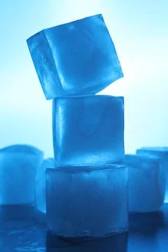 Stack of crystal clear ice cubes on light blue background. Color tone effect 写真素材