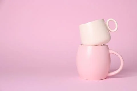 Stack of cups on pink background. Space for text Stock Photos