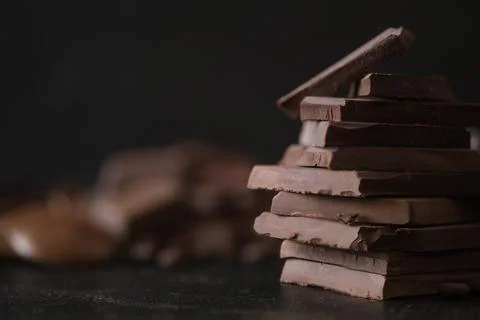 Stack of dark chocolate pieces empty space for text. Dessert food background. Stock Photos