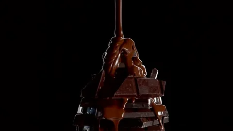A stack of dark chocolate pieces with molten chocolate pouring over them. Stock Footage 237597070
