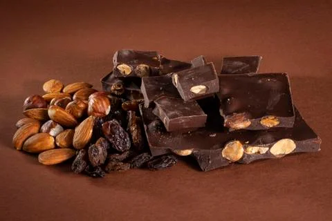 Stack of dark chocolate pieces with roasted almonds and raisins Stock Photos