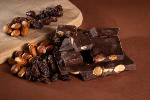 Stack of dark chocolate pieces with roasted almonds and raisins Stock Photos